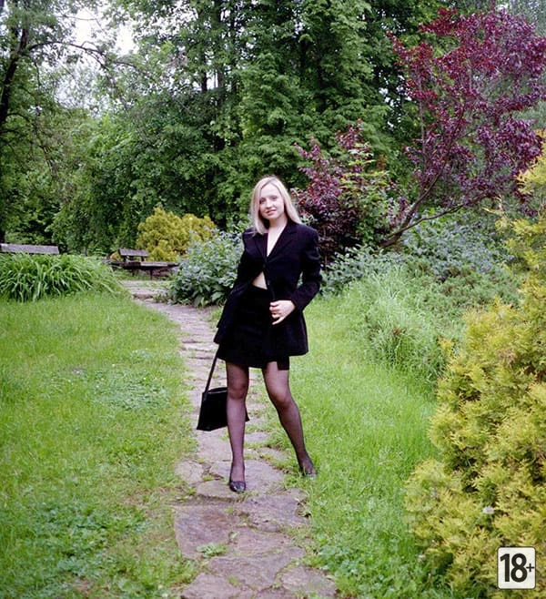 Блондинка в чулках курит в парке на скамье